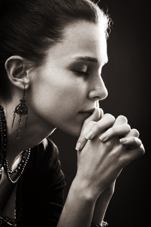 woman with eyes closed and hands folded in prayer
